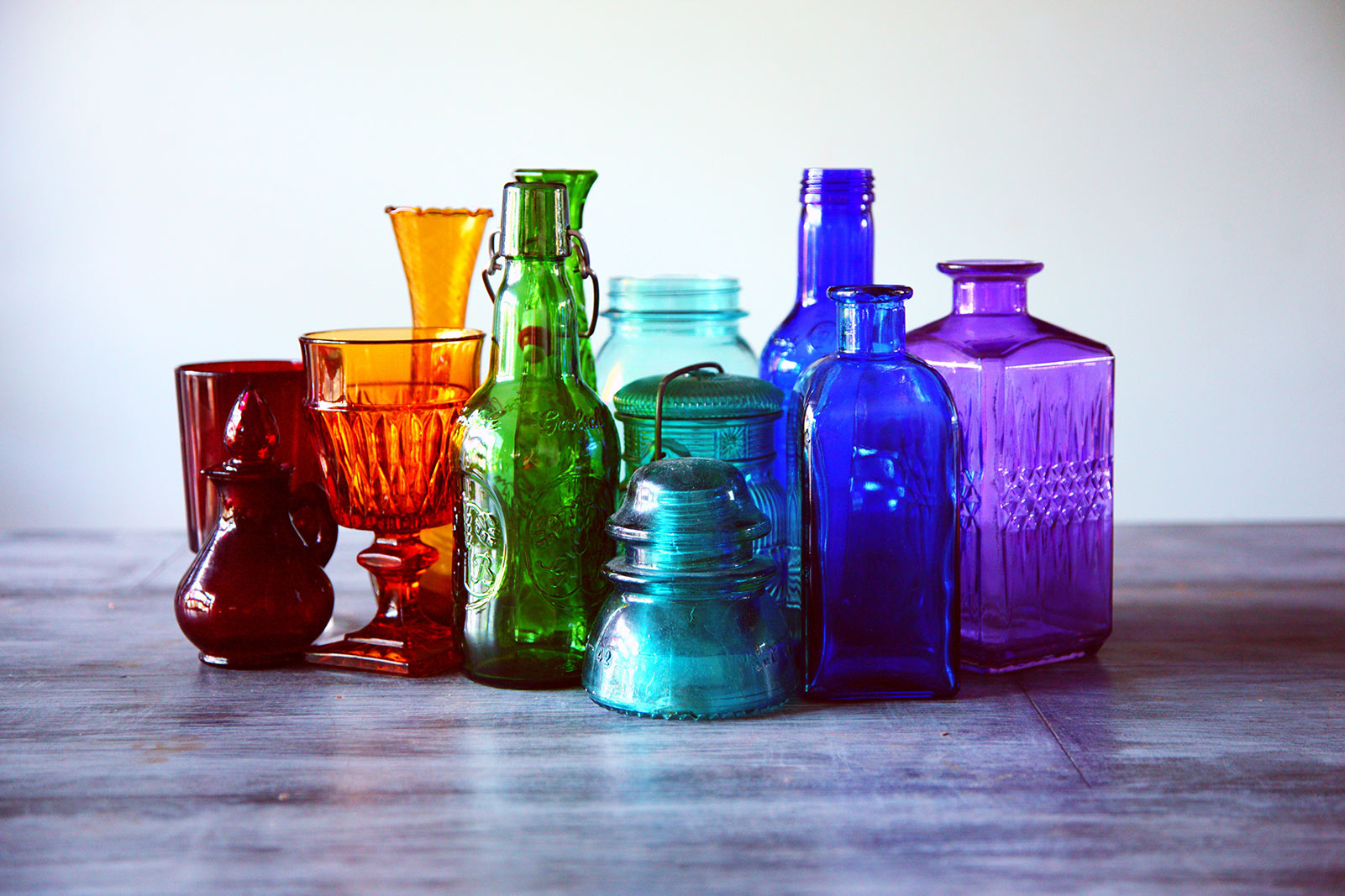 a group of colored glass jars and containers