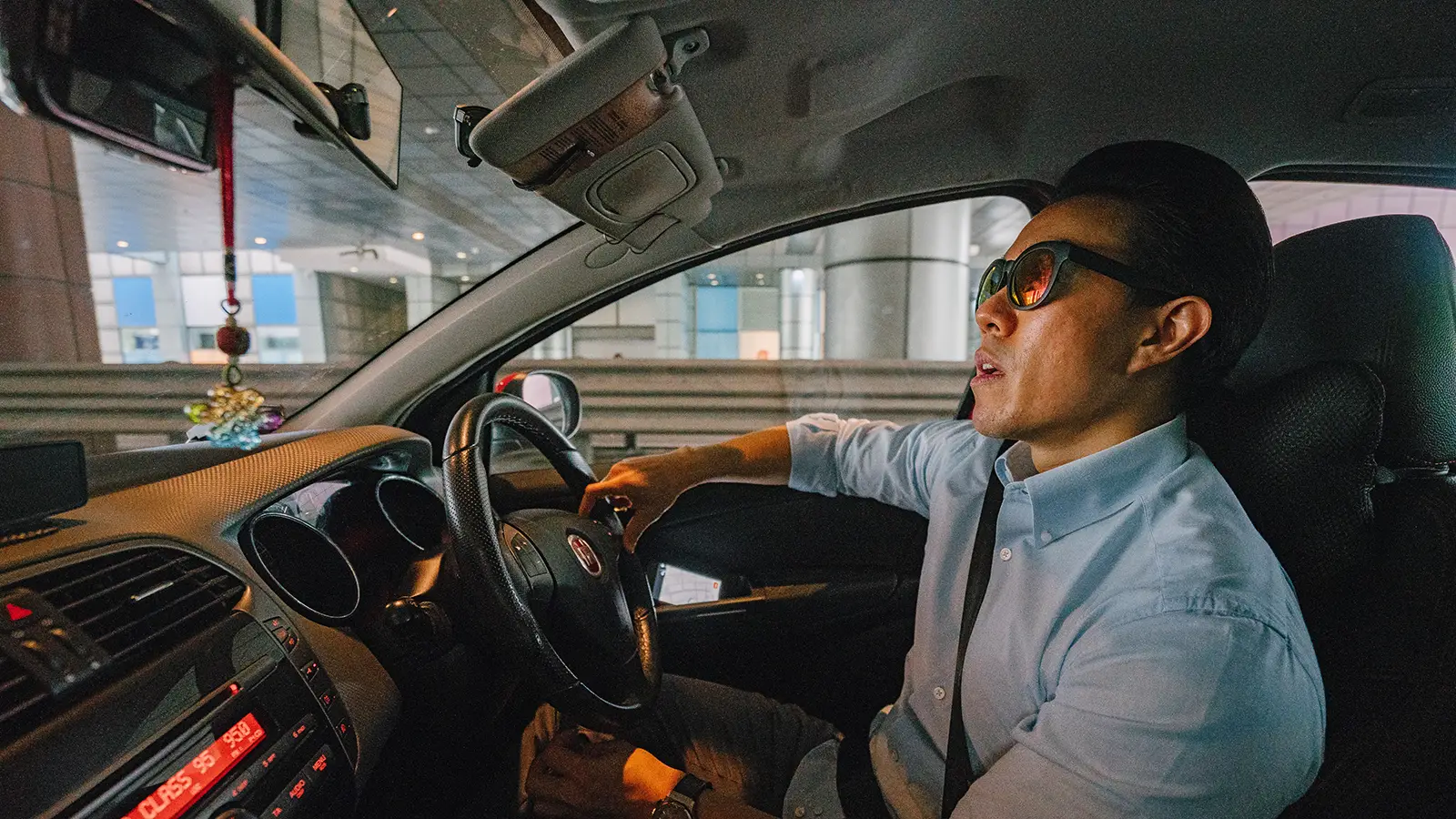 asian man in the driver seat of a car waiting in traffic