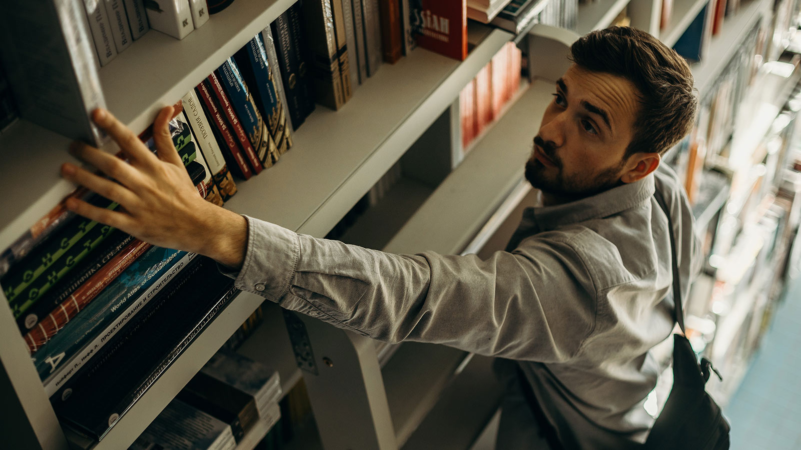 man reaching for a book