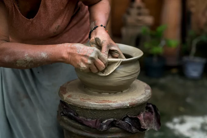 a woman creating a clay pot on a potter's wheel