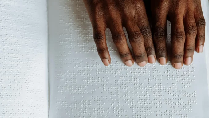 a black woman's hands using a page of braille to read