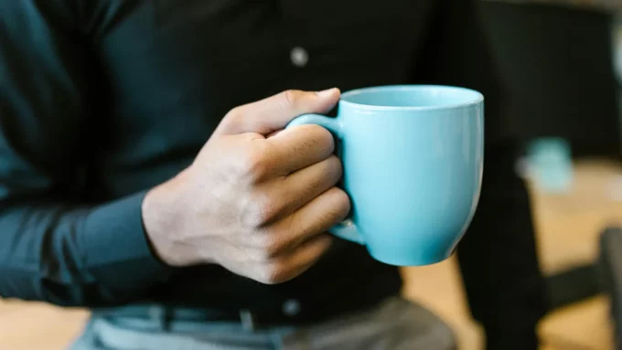 a white man holding a blue coffee mug by the handle