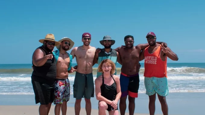a group of black and white people on a beach smiling in a group