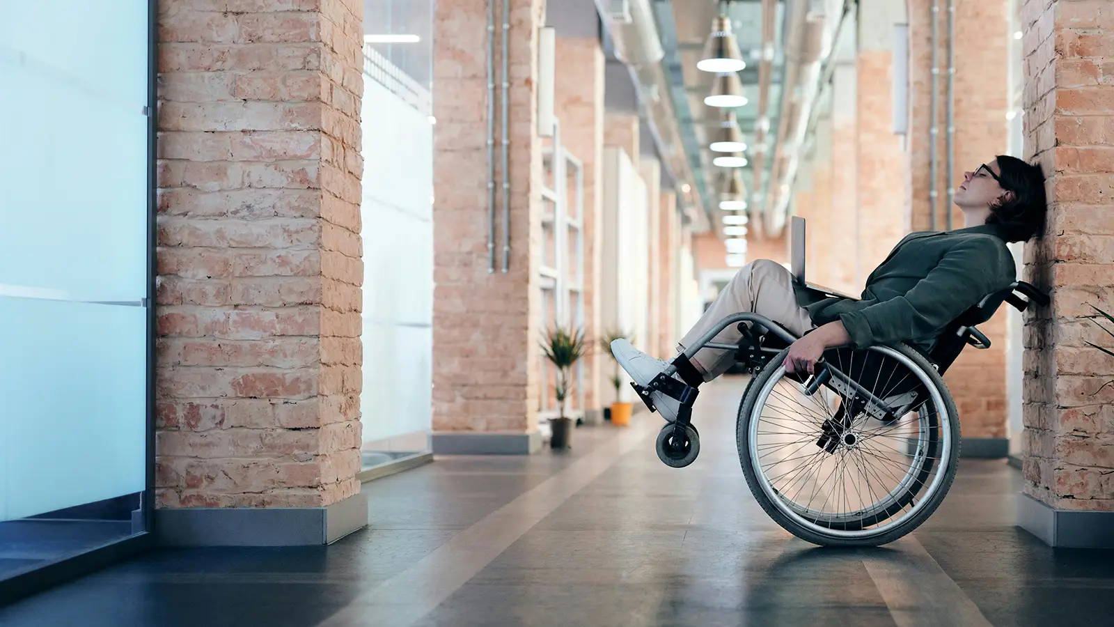 a white woman in a wheelchair rolled back, leaning against a wall