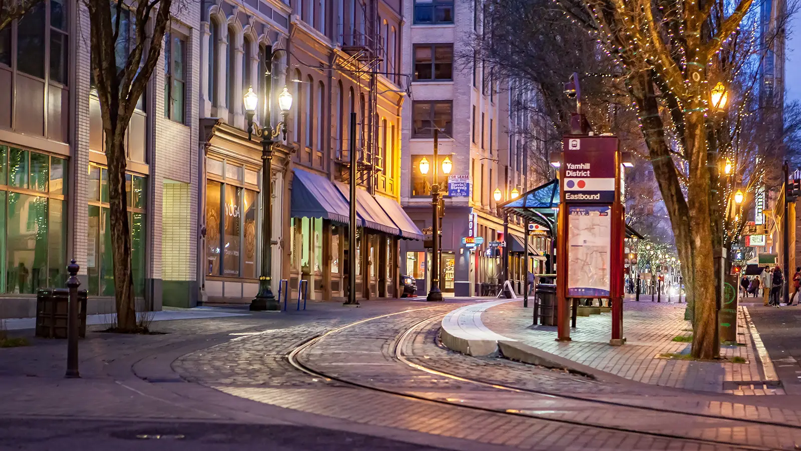 a city street at night with train tracks and a bus station