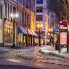 a city street at night with train tracks and a bus station