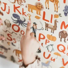 a closeup of a poster with the alphabet on it and a white girl pointing to letters