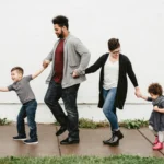 a mixed-race family of four, a male and female parent and two children walking on a sidewalk