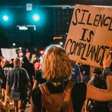 protesters at night with signs that say "no justice no peace"