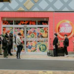 a line of people waiting in front of a store for it to open