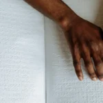 a black woman's hands using a page of braille to read