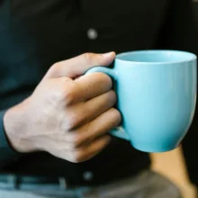 a white man holding a blue coffee mug by the handle
