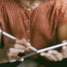 a black woman using a stylus to draw on an iPad screen