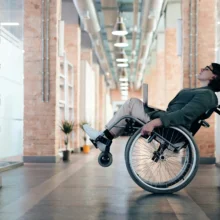 a white woman in a wheelchair rolled back, leaning against a wall