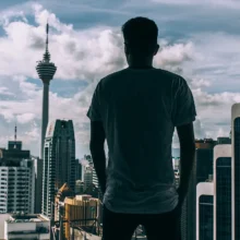 a man's silhouette looking out on a city in the distance