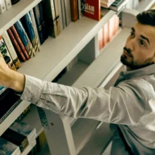 man reaching for a book