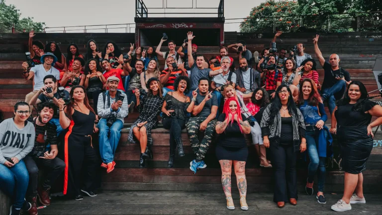 A group of 60 racially diverse people smiling at the camera with their arms raised