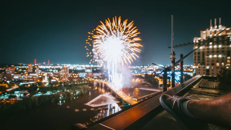 man viewing fireworks in a city from the roof