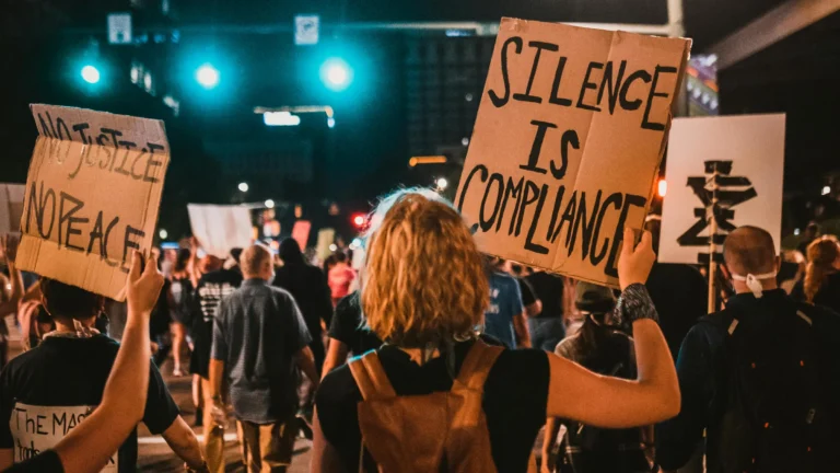 protesters at night with signs that say "no justice no peace"
