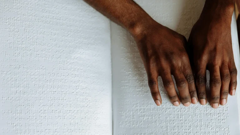 a black woman's hands using a page of braille to read