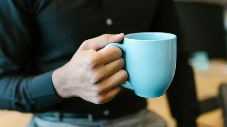 a white man holding a blue coffee mug by the handle
