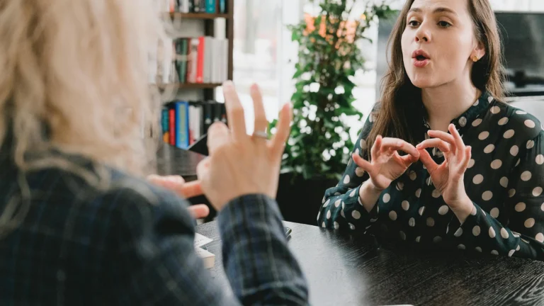 two white women using sign language to have a conversation with one another