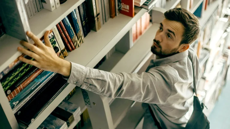 man reaching for a book