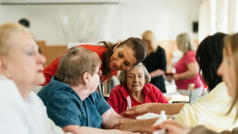 a group of older adult women sitting at a table at an assisted living commnity
